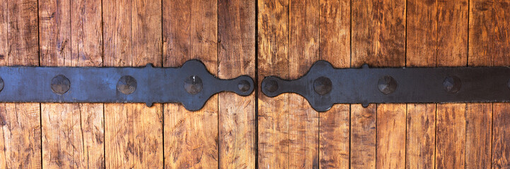 Fragment of closed old wooden gate with metal fittings