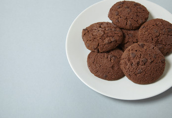 Fototapeta premium A plate full of chocolate chunk cookies on a grey background forming a page border