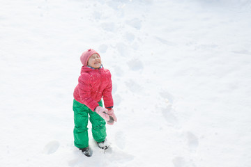 Fototapeta na wymiar Playful girl with braids playing in snow