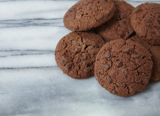 A pile of freshly baked chocolate chip cookies on a white marble background forming a page header