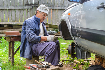 Elderly man repairing the front hub wheels.