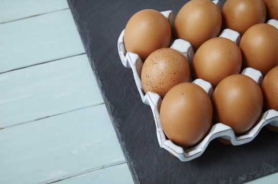 Chicken eggs on a blue wooden counter top background forming a page border
