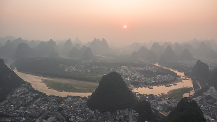 Breathtaking aerial view over beautiful karst mountain landscape  and Li River covered with haze or fog at sunset in Yangshuo County, China.
