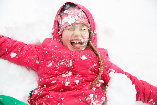 Playful girl with braids playing in the first snow