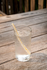 Glass water with ice on wooden table.