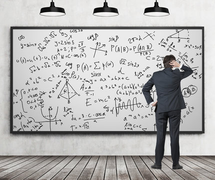 Man in suit looking at whiteboard with formulas