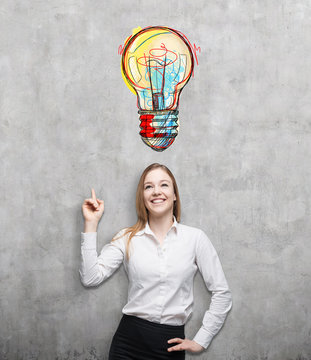 Blond woman pointing at large colorful light bulb