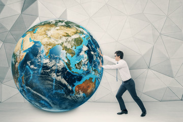 Man pushing globe in concrete room with white floor