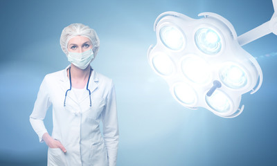 Woman surgeon wearing a mask and bright lamp