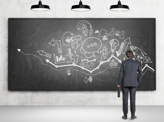 Businessman looking at blackboard with sketches