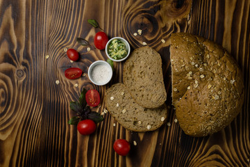 Bread slices decorated with sliced cherry tomatoes with a cup of butter and salt lying on a wooden background