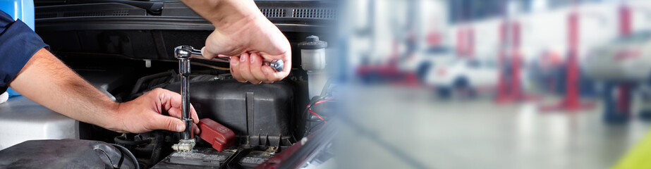 Hands of car mechanic with wrench in garage.