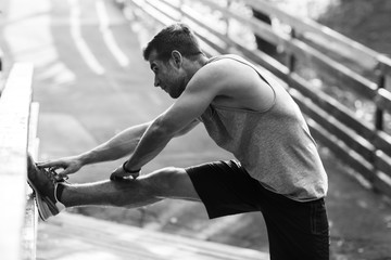 Obraz premium Młody sportowiec robi ćwiczenia rozciągające, czarno-białe zdjęcie