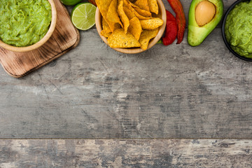 Nachos, guacamole and ingredients on wooden background

