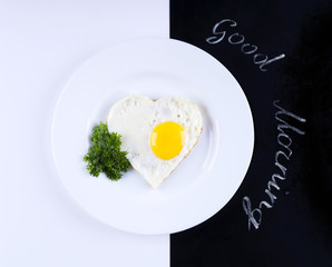 Scrambled eggs in a heart shape on a black and white background. Scrambled eggs for breakfast. Written good morning.