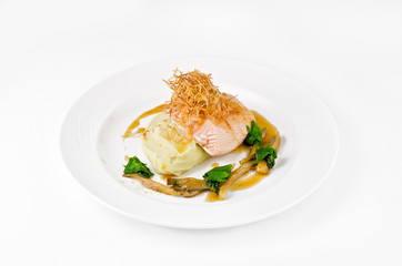 Salmon with mashed potatoes and gravy on a plate on a white background