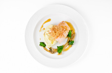 Salmon with mashed potatoes and gravy on a plate on a white background, top view
