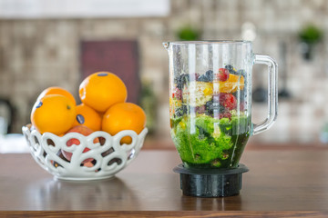 Mix of Fruits, Berries and Vegetables in a Mixer on the Table, Making Green Smoothie