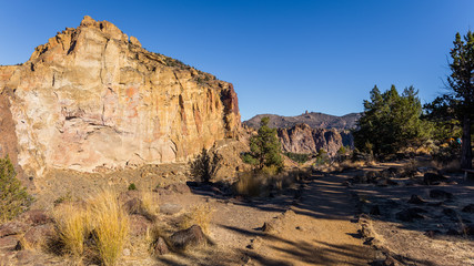 The path among the rocks. The sheer rock walls. Beautiful landscape of yellow sharp cliffs. Dry yellow grass grows on the slopes of the mountains. River flows in a valley Smith Rock state park, Oregon