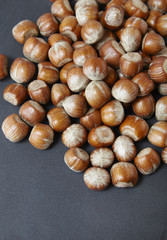 A pile of whole hazelnuts arranged on a rustic slate background