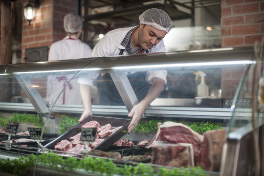 Butcher putting fresh meat on display in butchery