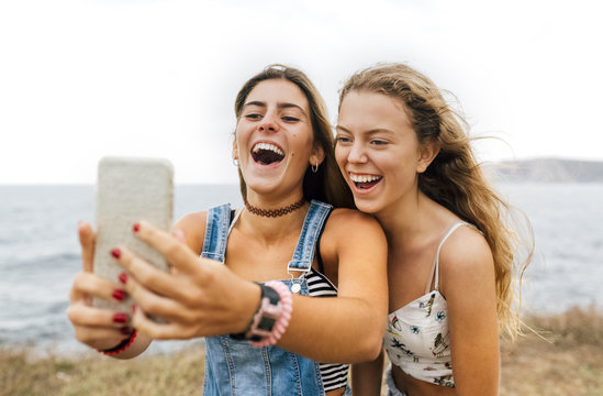 Two best friends taking selfie with smartphone at the coast