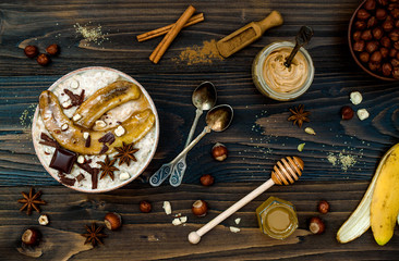 Healthy fall and winter breakfast bowl. Chai tea infused overnight oats porridge topped with caramelized bananas, raw dark chocolate and hazelnut butter. Flat lay. Ideal Christmas morning meal 