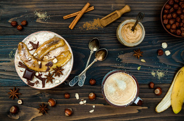 Healthy fall and winter breakfast bowl. Chai tea infused overnight oats porridge topped with caramelized bananas, raw dark chocolate and hazelnut butter. Flat lay. Ideal Christmas morning meal 