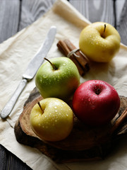 Apples with khife and cinnamon water drops on craft paper black wooden table, back light
