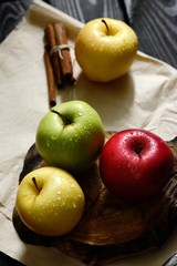 Apples with khife and cinnamon water drops on craft paper black wooden table, back light