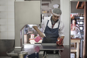 Butcher cleaning work surface in butchery