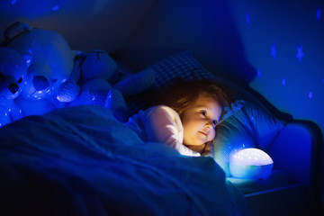 Little girl in bed with night lamp