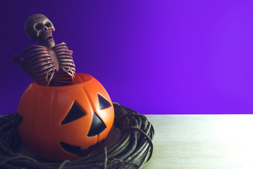 skeleton in ghost halloween cup bucket and wood vine on purple background