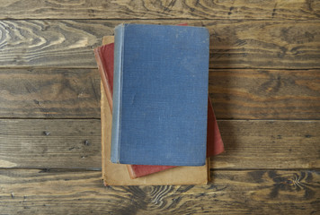 A pile of hard cover journals on an old wooden desk top background