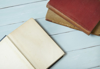 A stack of ages story books on a blue wooden desk top background