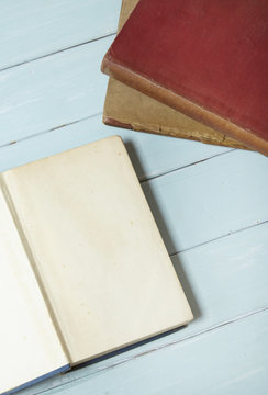 A stack of old library books on a blue wooden desk top background