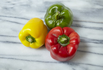 Colorful sweet bell peppers on a white marble counter top background