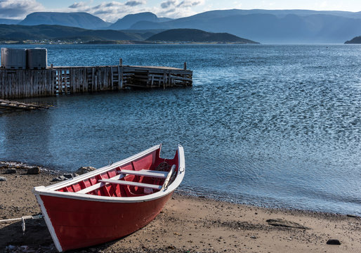 small wooden red fishing boat on shore