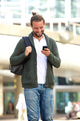 Smiling man with beard looking down at cellphone