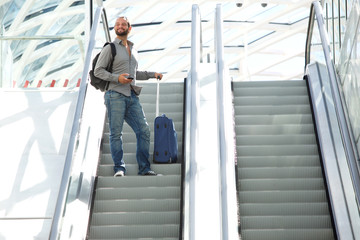 Travel man standing on escalator with bags