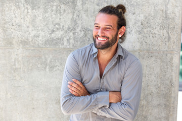 Smiling modern man with beard standing with arms crossed - obrazy, fototapety, plakaty
