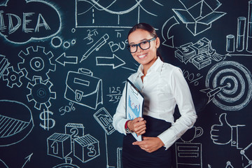 Portrait of a asian business woman in glasses on dark background with pictures charts in hand