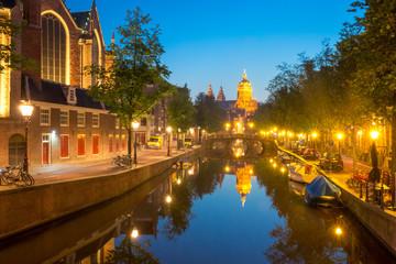 Fototapeta na wymiar Night red-light district De Wallen, canal, bridge, Basilica of Saint Nicholas and its mirror reflection, Amsterdam, Holland, Netherlands. Long exposure.