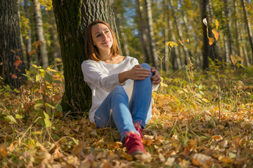 Girl sitting under a tree in autumn forest