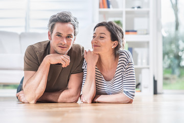 At home,  a young couple is lying on the wooden floor