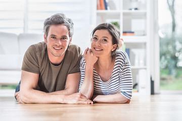 At home,  a young couple is lying on the wooden floor