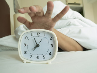 white alarm clock and sleeping man