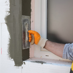 Worker spreading  mortar over styrofoam wall insulation with trowel