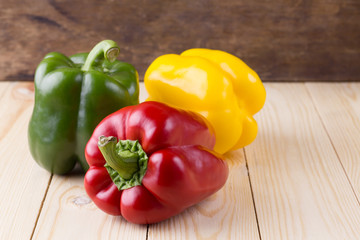 Fresh sweet peppers three color red, yellow, and  green on woode
