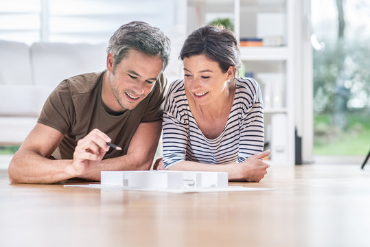 At Home, Young Couple Study A Model House Of A Building Project